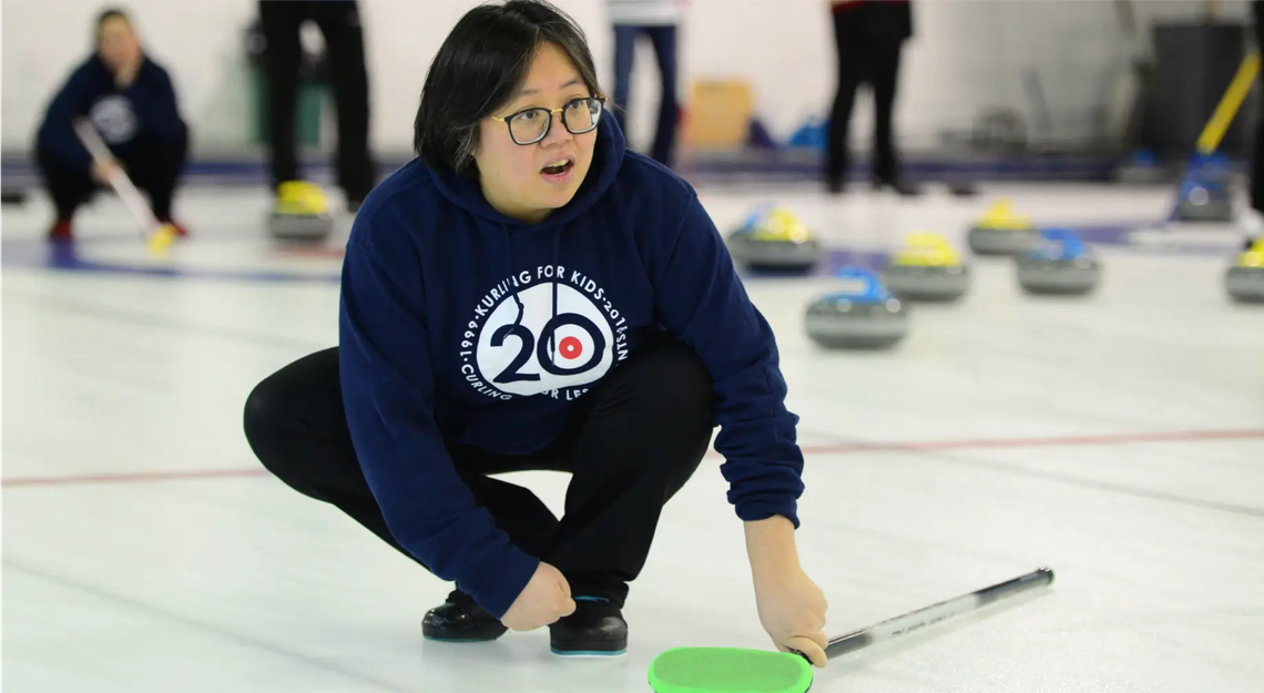 Un joueur de curling s'est accroupi sur la glace