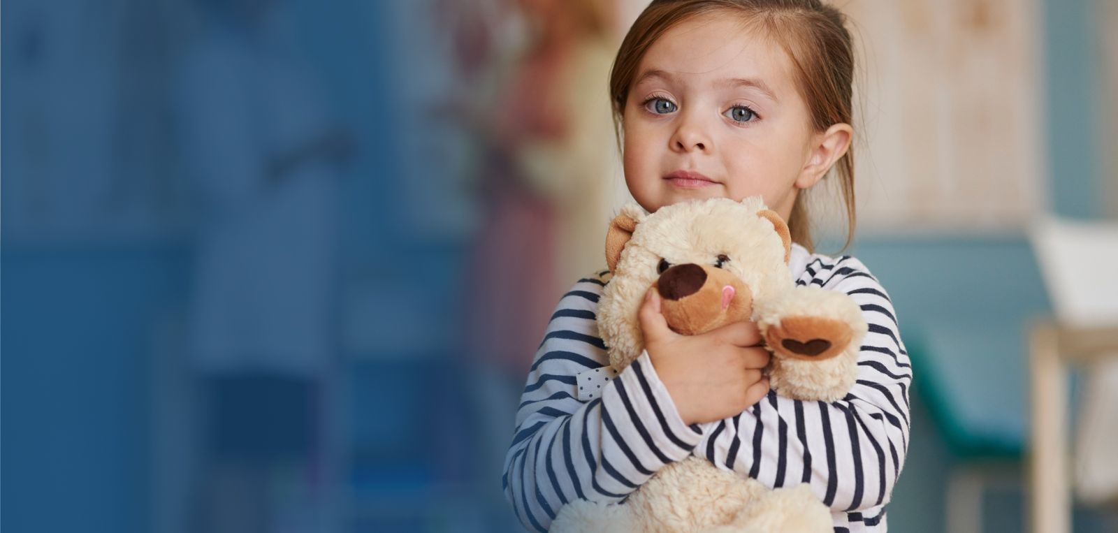 petite fille serrant un ours en peluche dans ses bras